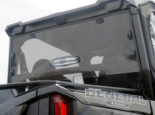 Close-up of the Polaris General Rear Vented Windshield-Tinted-Gp 2016+ on a black vehicle, showing its tinted transparent glass, latch hinges, angular frame, part of a tail light, and the “GENERAL” logo with stars at the bottom right.