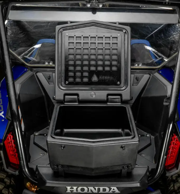 Close-up of the rear cargo area of a blue Honda Talon 1000 featuring an open Cooler/Cargo Box with a hinged lid, showing its empty interior. The vehicle’s interior structure and part of the roll cage are visible in the background.