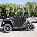 A CF Moto UFORCE 800 with Half Doors by Dirt Specialties, black rims, rugged off-road tires, and roll cage is parked on gravel. The side-by-side seats two, with green trees in the background on a sunny day.