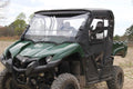 A green Yamaha Viking UTV (2015+) with a black roof, transparent windshield, large rugged tires, open cargo bed, and black Yamaha Viking Full Frame Door Kit is parked on a dirt field. Trees can be seen in the background.