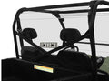 A close-up of the Polaris Ranger Full-Size 2010+ with Round Tubing Rear Windshield-Vented (fits 2010-2019 models) shows a clear rear windshield, black roll bars, two headrests, a dashboard on the right, and a warning label on the back panel.