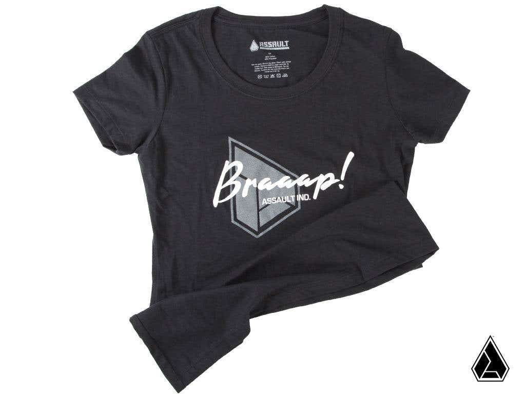 The Assault Industries Braaap Womens Tee is a black t-shirt with a bold geometric triangle logo reading Braaap! in white script and ASSAULT NO. below. The collar tag reads ASSAULT, and a small triangle logo accents the bottom right corner.