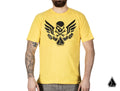 A person with a beard and a tattoo sleeve wears the Assault Industries Raider Yellow T-Shirt, featuring a black skull, wings, and crossed wrenches graphic on the chest. A small black logo appears at the bottom right corner of the image.