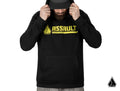 A bearded man in a black Assault Industries Bomb Hoodie with a yellow logo across the chest and cap looks down, holding the hood with both hands. The background is white, with a small triangular logo in the bottom right corner.