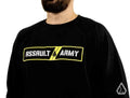 A bearded man wears the Assault Industries Army Sweatshirt, which has ASSAULT ARMY in bold white letters on a black and yellow background with triangular logos, set against a white backdrop.