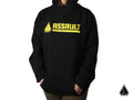 A person wears the Assault Industries Classic Logo Hoodie, featuring bold yellow “ASSAULT Industries” text and logo on the chest. Their hands are in the front pocket. The image has a plain white background with a small triangular logo at the bottom right.