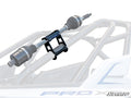 The Spare Axle Cage Mount is shown in black metal, securely holding a drive axle on an off-road vehicles roll cage. The semi-transparent view highlights its function for axle storage or transport, with the SuperATV logo visible in the corner.