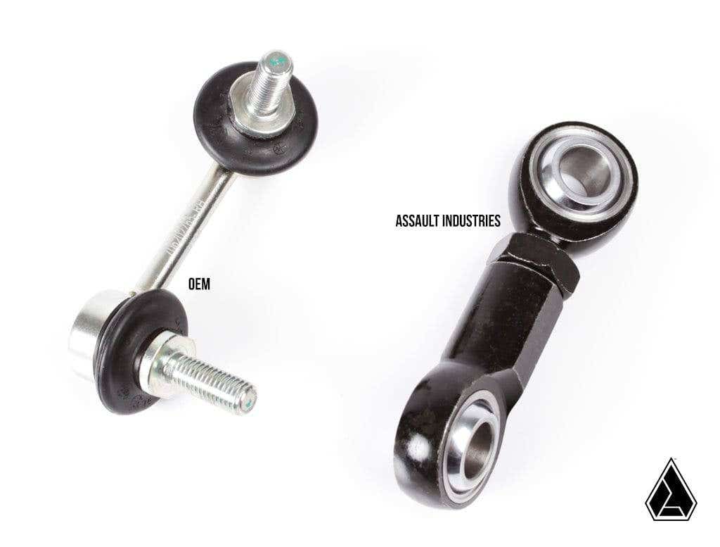 The image compares two sway bar end links: on the left, a silver OEM with rubber bushings; on the right, a black Assault Industries Heavy Duty Front Sway Bar End Link (Fits: Can-Am Maverick X3) with a metal heim joint. Both are labeled, with a triangular 