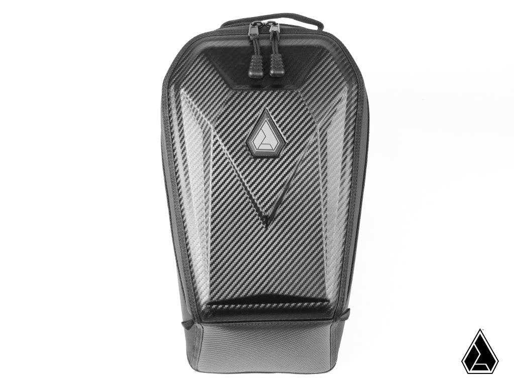 The Assault Industries RUXAK Glovebox for Polaris RZR Pro XP is a black, hard-shell zippered case with a carbon fiber pattern, angular textured lines, and a triangular logo on the front, shown upright against a plain white background.