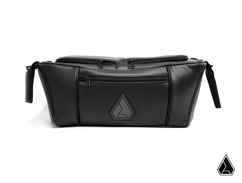 The Assault Industries UTV Storage Bag (Fits: Polaris RZR) is a sleek black duffel with textured material, side handles, main zipper, front zip pocket, and stitched geometric logo. Displayed on a white background with a small logo in the bottom right.