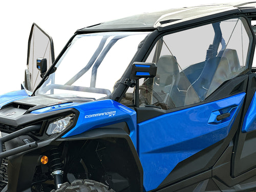 A Can Am Commander Venting Polycarbonate Upper Doors Kit (2021+) is installed on a blue and black off-road vehicle with clear doors, rugged tires, side mirrors, roll cage, and Commander labeled on the side. Shown close-up from the front side on a white ba