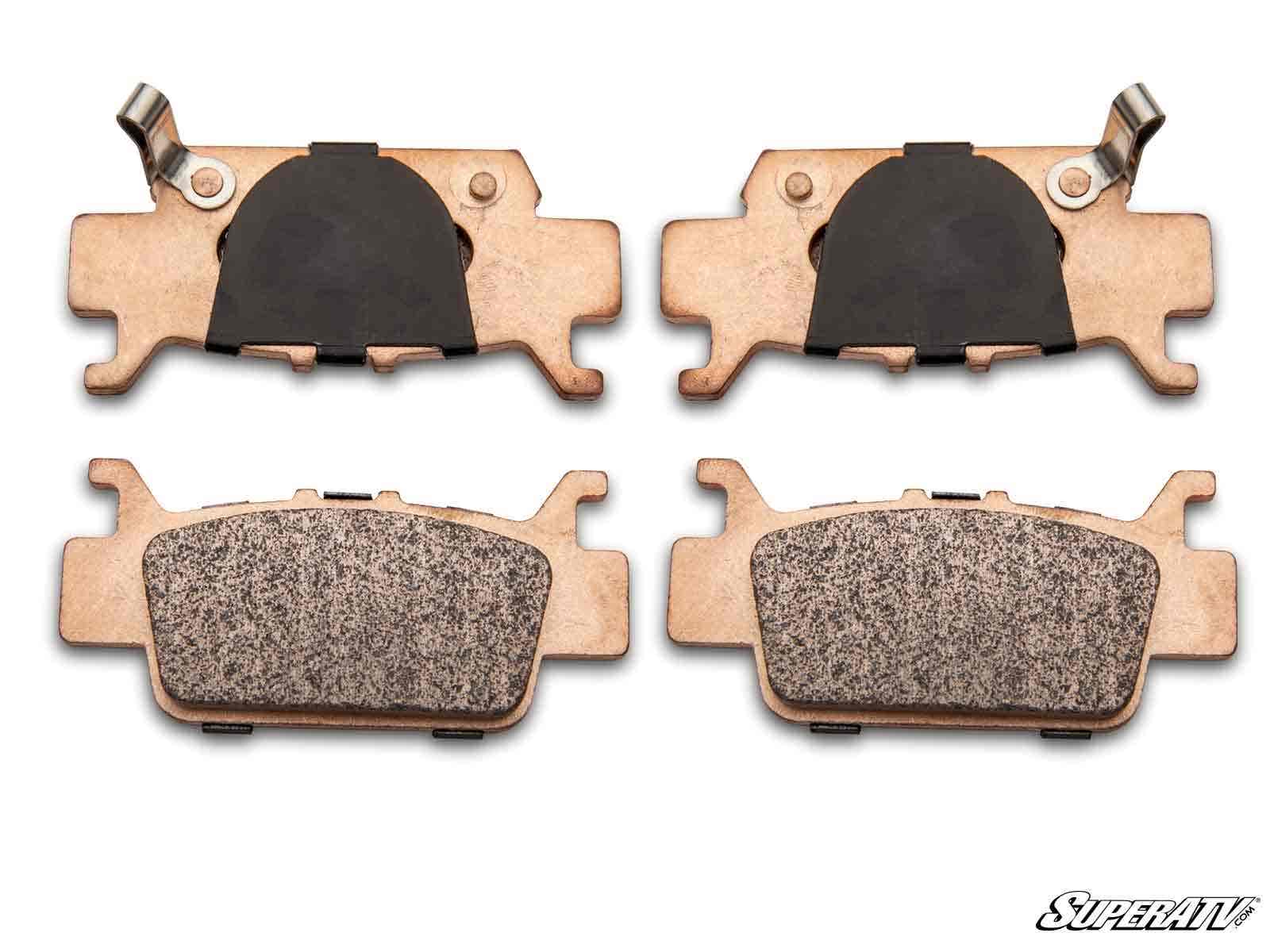 Four Honda Talon 1000 Sintered Brake Pads are arranged in two rows on a white background. The top row shows the backs with black sections and metal clips; the bottom row displays the textured friction surfaces. The SuperATV logo is visible in the corner.