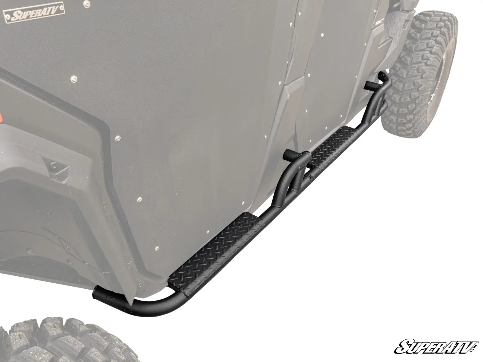 A close-up of Can-Am Defender Max Heavy Duty Nerf Bars—black metal with a diamond plate step—mounted below the doors and above rugged tires on an off-road utility vehicle, offering enhanced side protection.