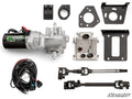 The Can-Am Maverick X3 Power Steering Kit is displayed on a white background, showing a silver electric power steering motor, wiring harness, couplers, brackets, metal shaft, black control box, connectors, and a SuperATV logo in the bottom right.