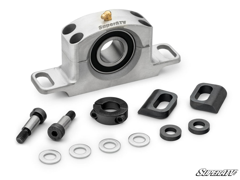 A silver Can-Am Maverick Trail Heavy-Duty Carrier Bearing with a black rubber seal, shown with two black bolts, five metal washers, a black collar, two rectangular mounting blocks, and the SuperATV logo at bottom right.