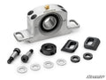 A silver Can-Am Maverick Trail Heavy-Duty Carrier Bearing with a black rubber seal, shown with two black bolts, five metal washers, a black collar, two rectangular mounting blocks, and the SuperATV logo at bottom right.