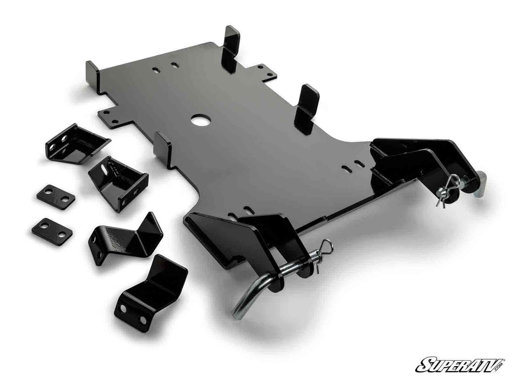 A Can-Am Commander Plow Pro Snow Plow Mount kit in black metal, with mounting brackets, plates, and hardware laid out on a white background. The large center plate has cutouts and attachment points; SuperATV logo is bottom right.