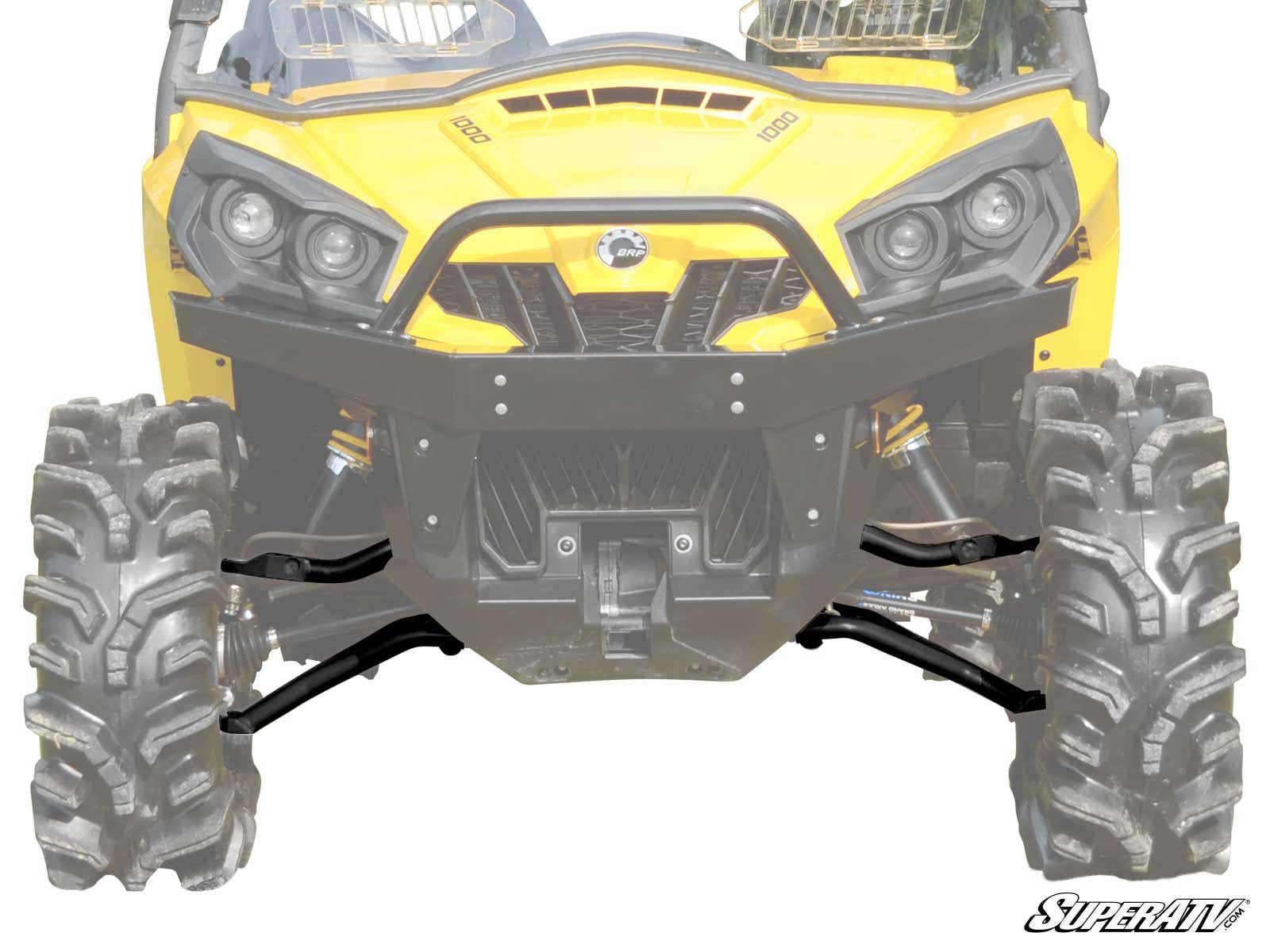 Front view of a yellow off-road utility vehicle with large, rugged tires, black bumper, angular headlights, and visible suspension featuring Can-Am Commander High Clearance 1.5 Forward Offset A-Arms. SuperATV logo is in the bottom right corner.