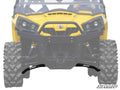Close-up front view of a yellow off-road utility vehicle showing rugged tires and Can-Am Commander High Clearance Lower A-Arms by SuperATV. The black suspension components are highlighted, with the SuperATV logo at the bottom right corner.