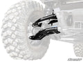 Close-up of a Can-Am Defender HD9 Atlas Pro 2 Rear Offset A-Arms’ front suspension and tire. The image focuses on the heavy-duty black suspension components with the SuperATV logo at the bottom right, fading out the rest of the vehicle.