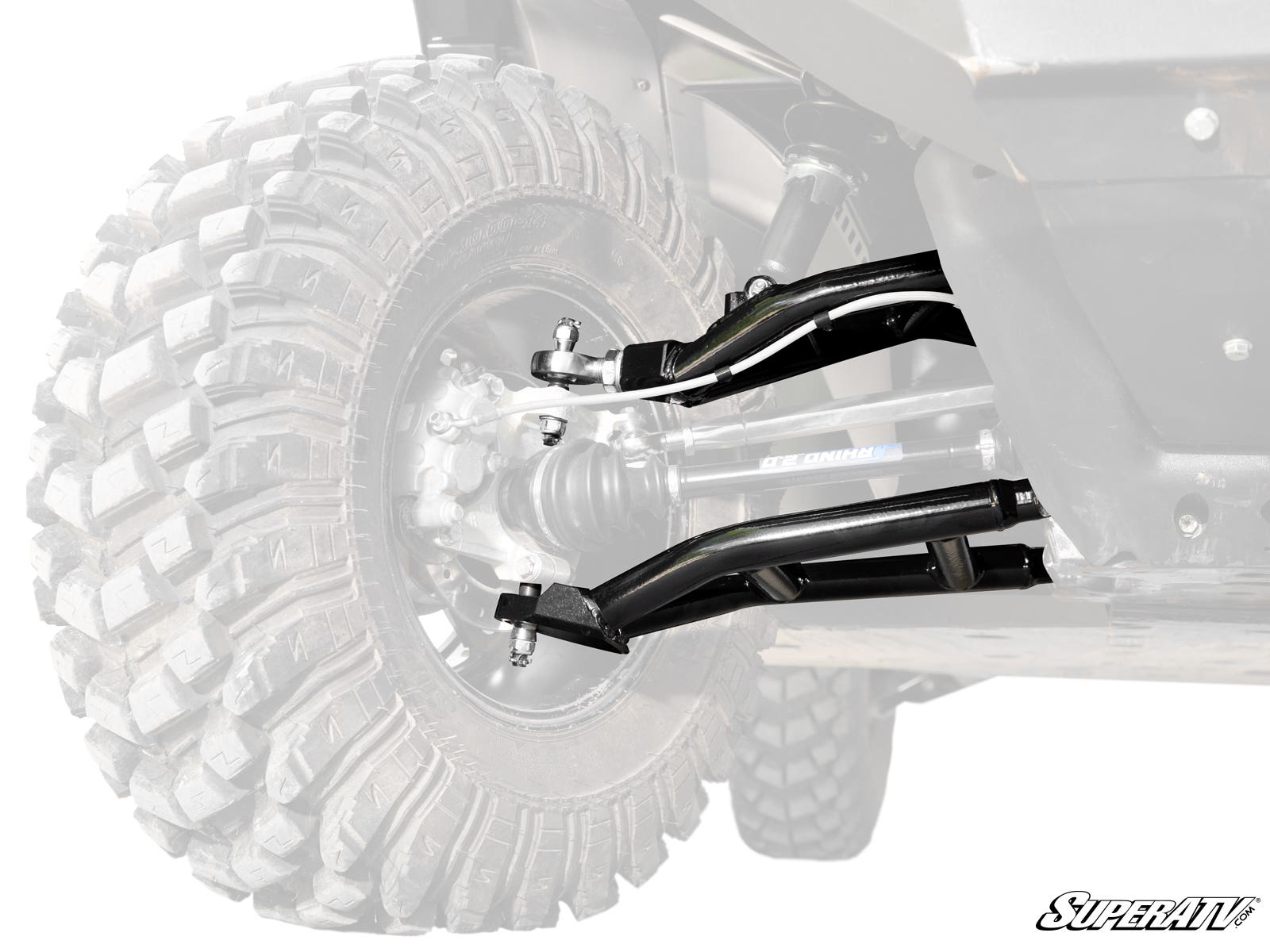 Close-up of the Can-Am Defender HD8 Atlas Pro Heim Joint 1.5 Forward Offset A-Arms suspension system with large rugged tire, dual black control arms, joints, and SuperATV branding visible. Only the suspension components and tire are in focus; rest is fade