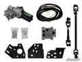 The Can-Am Maverick Power Steering Kit is displayed on a white background, featuring a motor, wiring harness, bolts in plastic bags, control module, two metal brackets, black steering shaft, and mounting plates.