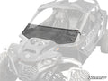 A Can-Am Maverick R Half Windshield, made of tinted polycarbonate with a vent for airflow, is installed on a rugged black Maverick side-by-side. The windshield covers the front cockpit; the vehicle is partially faded to highlight it.