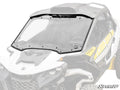 A Can-Am Maverick R Scratch-Resistant Full Windshield, framed in black and securely mounted on a yellow and white vehicle, is shown with the SuperATV logo in the lower right corner of the image.