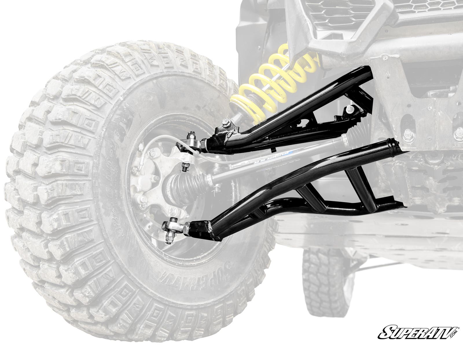 Close-up of Can-Am Maverick X3 Atlas Pro Heim Joint 1.5 Forward Offset A-Arms in shiny black, attached to a rugged off-road vehicle with large knobby tires; yellow coil spring stands out. “SuperATV” logo appears bottom right. Background vehicle is faded f