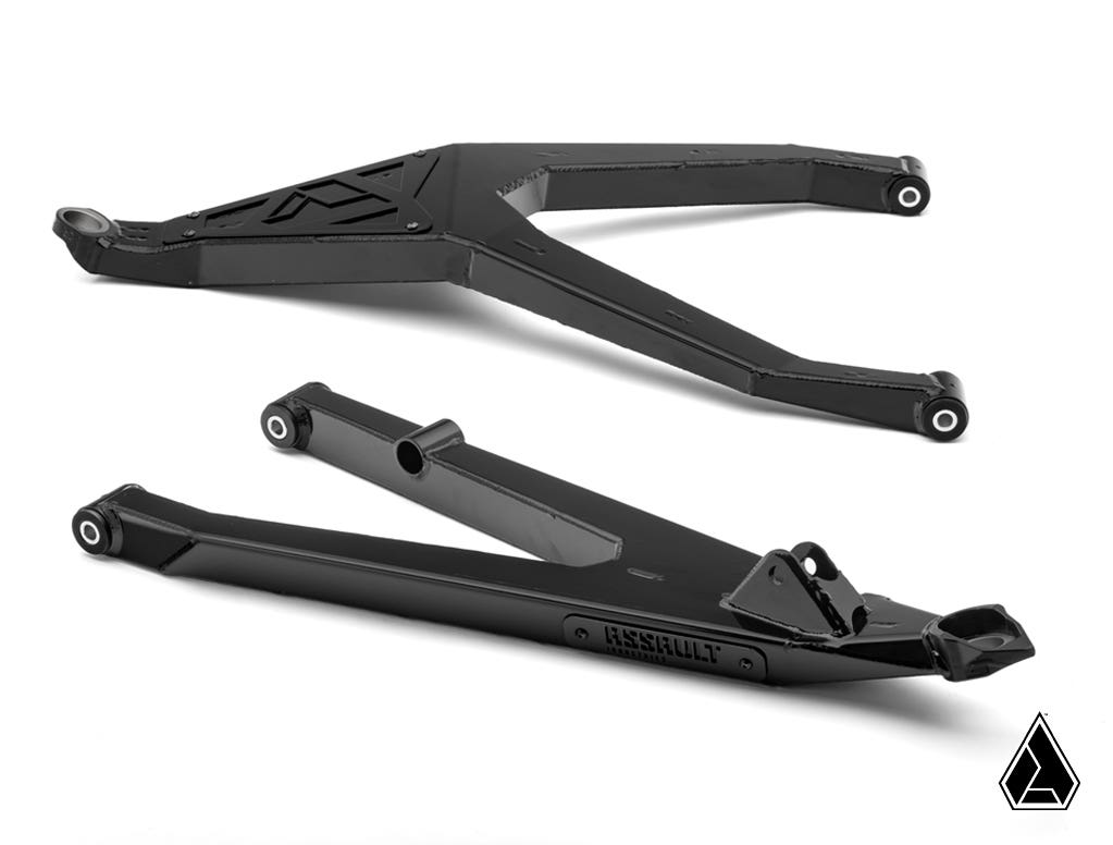 Two black metal Assault Industries Can-Am Maverick X3 High-Clearance Boxed A-Arms are shown on a white background. The upper arm is Y-shaped with cutouts; the straighter lower arm is labeled Assault. The Assault Industries logo appears in the corner.