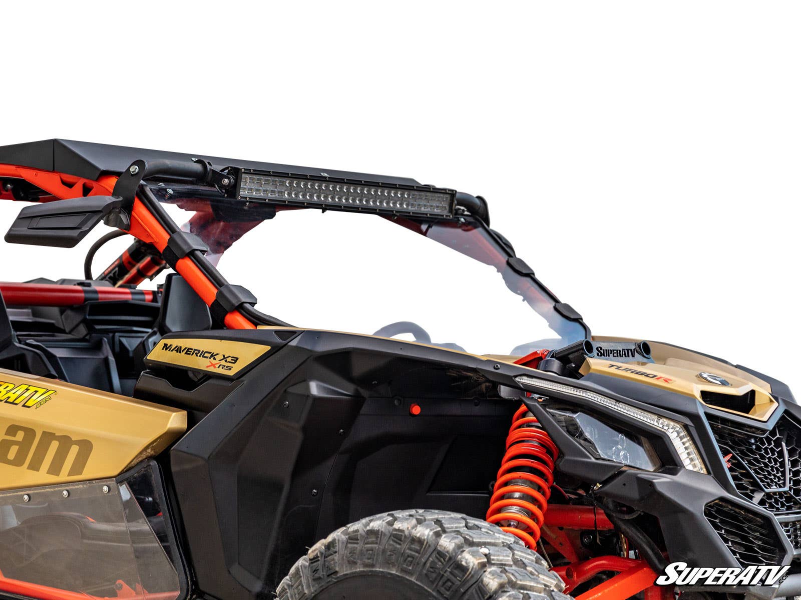 A close-up of a gold and black Can-Am Maverick X3 featuring the Full Windshield, a mounted LED light bar, orange suspension springs, rugged tires, and the SuperATV logo in the bottom right corner, all set against a white background.