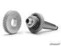 The image features two metallic gears from the Can-Am Maverick X3 Transmission Gear Reduction Kit: one circular gear with a central hole, and another mounted on a shaft. Both have precise teeth. The “SuperATV” logo is in the bottom right on a white backgr
