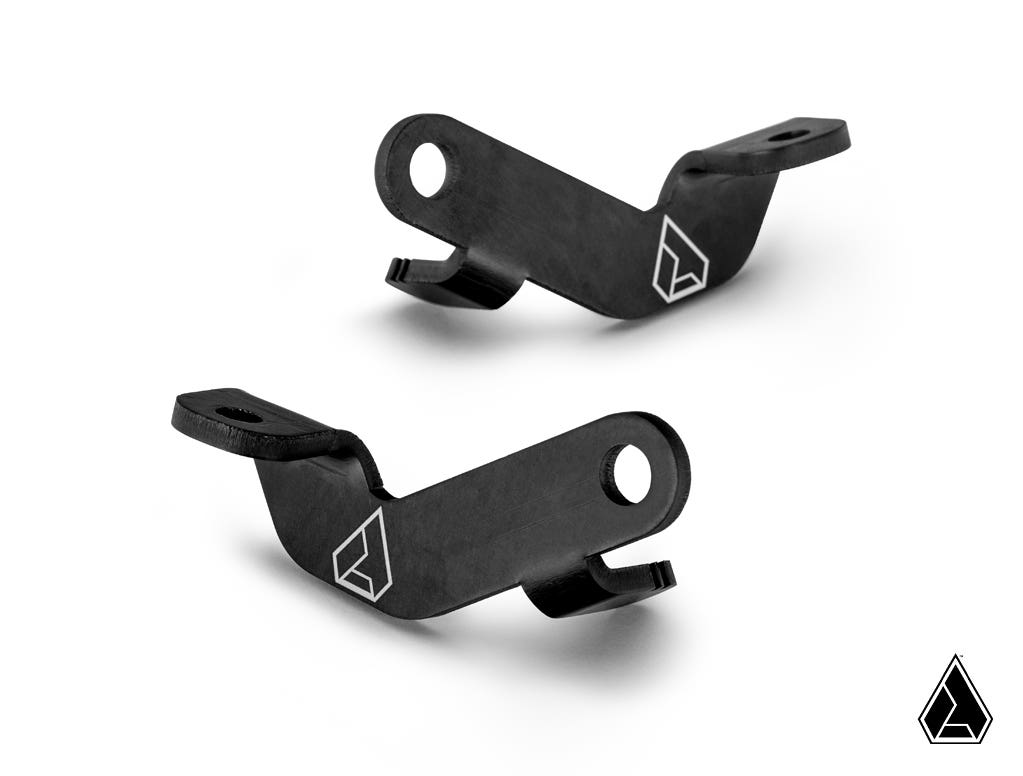 Two identical black Assault Industries Side Mirror Light Bracket Kit brackets with angled shapes and large circular holes rest on a white background. Each bracket features a white geometric logo, with a smaller version in the lower right corner.