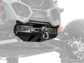 Close-up of a Can-Am Maverick X3 Ready-Fit Winch mounted under the front of an off-road vehicle with rugged suspension, red coil springs, and a black protective winch housing. The SuperATV logo is shown in the bottom right corner.