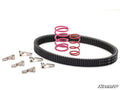 A Can-Am Maverick X3 Rev1 Clutch Kit, including a black drive belt, two coiled springs (large pink, small red), and six cam arms, is displayed on a white surface with the SuperATV logo in the bottom right corner.