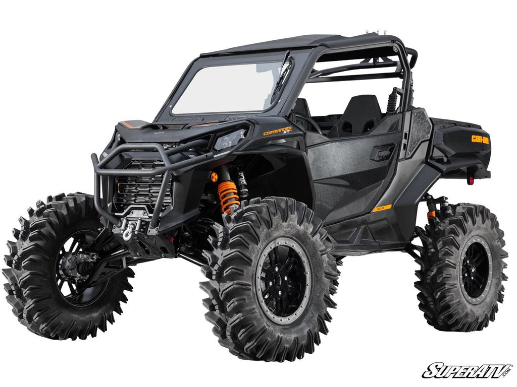 A Can-Am Maverick Sport with a 6 Lift Kit features black off-road styling, oversized mud tires, orange suspension springs, a roll cage, sturdy front bumper, closed doors, and a partially open windshield. SuperATV logo shown bottom right.