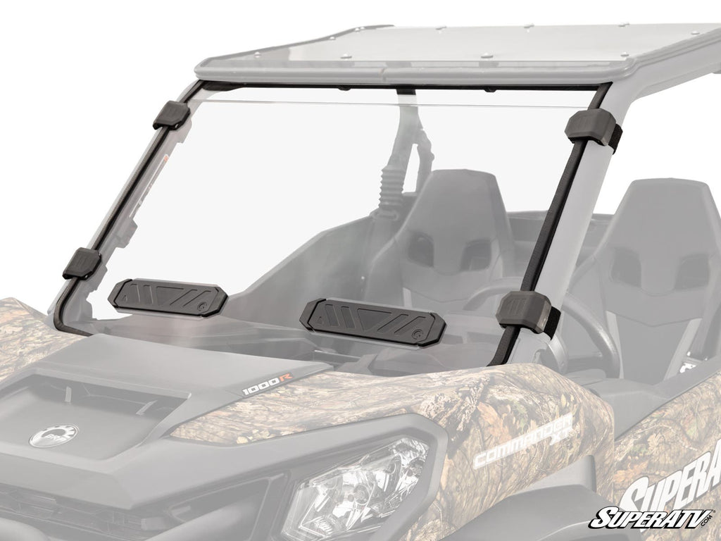 A Can-Am Commander fitted with the Vented Full Windshield featuring a clear, full camo-patterned design, two black base vents, secure black mounts, bucket seats, protective roof, and the SuperATV logo in the lower right corner.