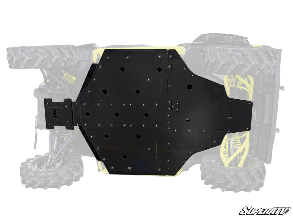 The Can-Am Defender Full Skid Plate, featuring the SuperATV logo, is a black metal plate secured with multiple screws to the underside of an off-road vehicle with large rugged tires, protecting most of the chassis.