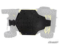 The Can-Am Defender Full Skid Plate, featuring the SuperATV logo, is a black metal plate secured with multiple screws to the underside of an off-road vehicle with large rugged tires, protecting most of the chassis.