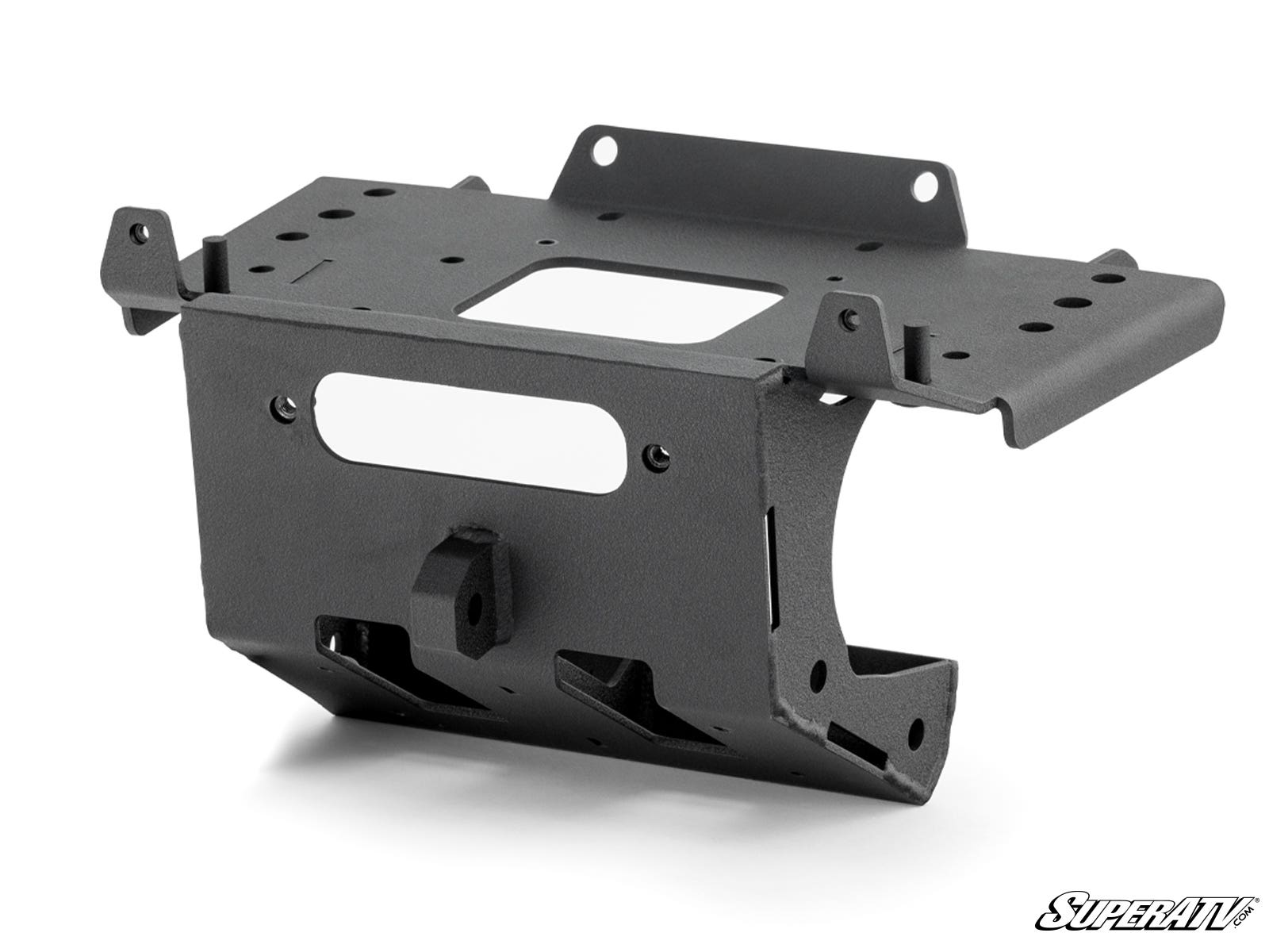 The Can-Am Maverick R Winch Mounting Plate is a black, rectangular metal bracket with cutouts and flanges for secure attachment. It features a matte finish and is pictured angled on white with the SuperATV logo in the bottom right corner.