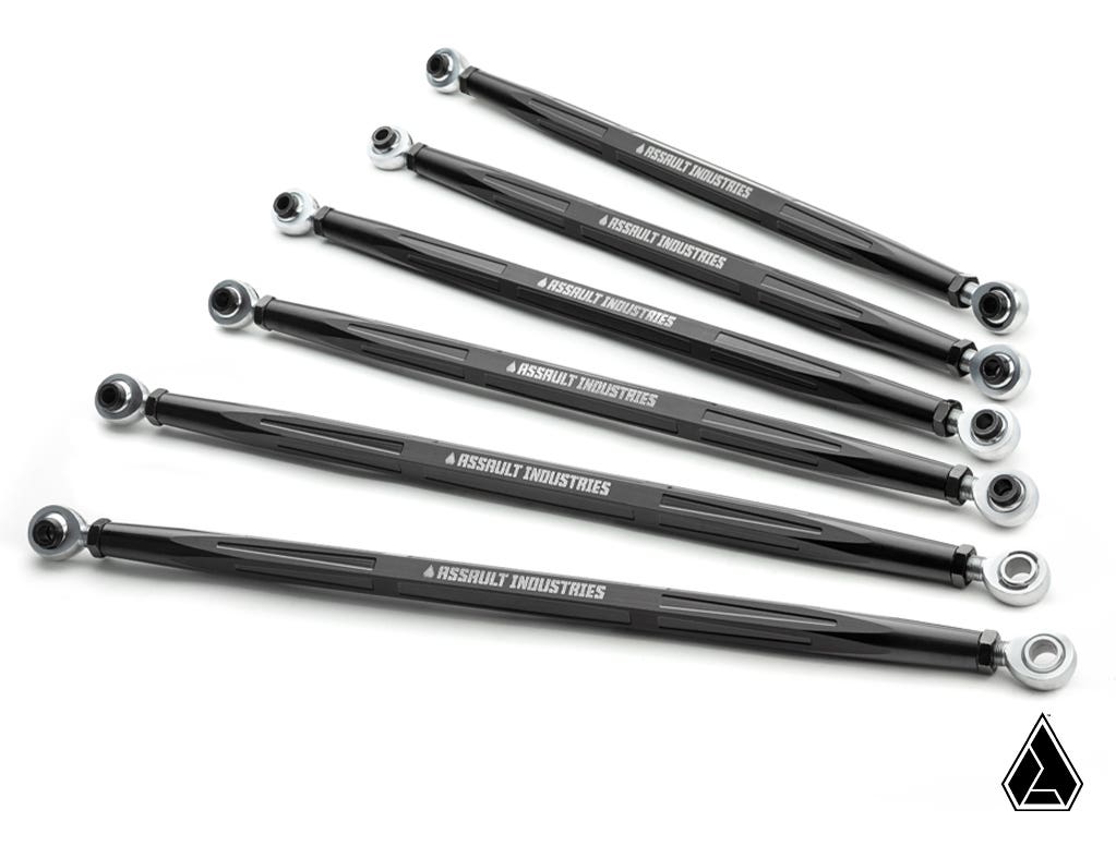 Six black metal Assault Industries Can-Am Maverick R Turret Style Quick Camber Radius Rods with spherical rod ends are arranged diagonally on a white background. Each arm features white branding, with a small geometric logo in the lower right corner.