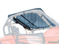 A Can-Am Maverick Tinted Roof is mounted with four clamps on the roll cage of an orange off-road vehicle, with the roof, body, and roll cage partially visible. The SuperATV logo appears in the bottom right corner.