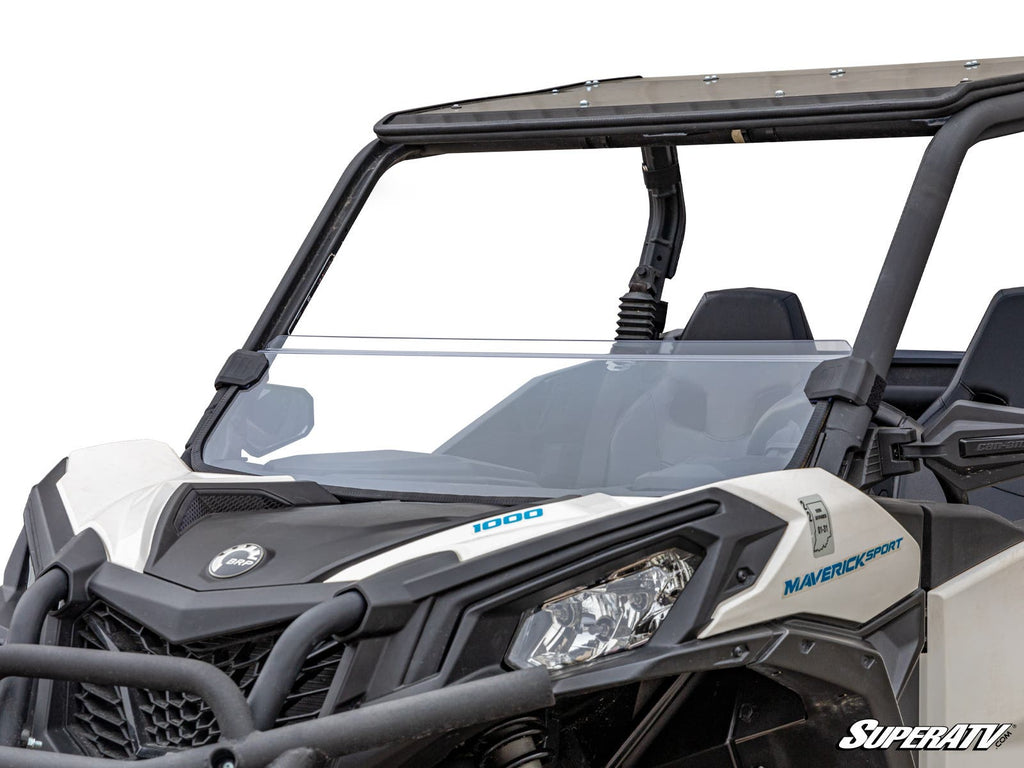 A close-up front view of a white Can-Am Maverick Sport 1000 with a Can-Am Maverick Sport Half Windshield installed, featuring tinted upper and clear lower panels. The ATV has angular headlights, a black roll cage, and rugged bumper against a white backgro