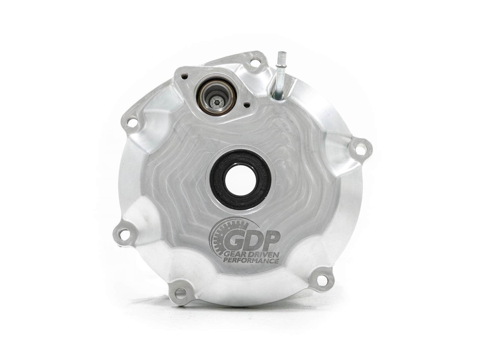 A circular, silver metal cover for the Can-Am Maverick X3 Pin Locker Differential features four bolt holes, a central black opening, a smaller upper opening, machined patterns, and the “GDP Gear Driven Performance” logo etched near the bottom.
