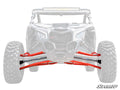 Front view of an off-road vehicle with faded chassis and wheels, highlighting bright red A-arms and suspension from the Can-Am Maverick X3 Long Travel Kit. The SuperATV logo appears in the bottom right, with A-arms centered prominently.