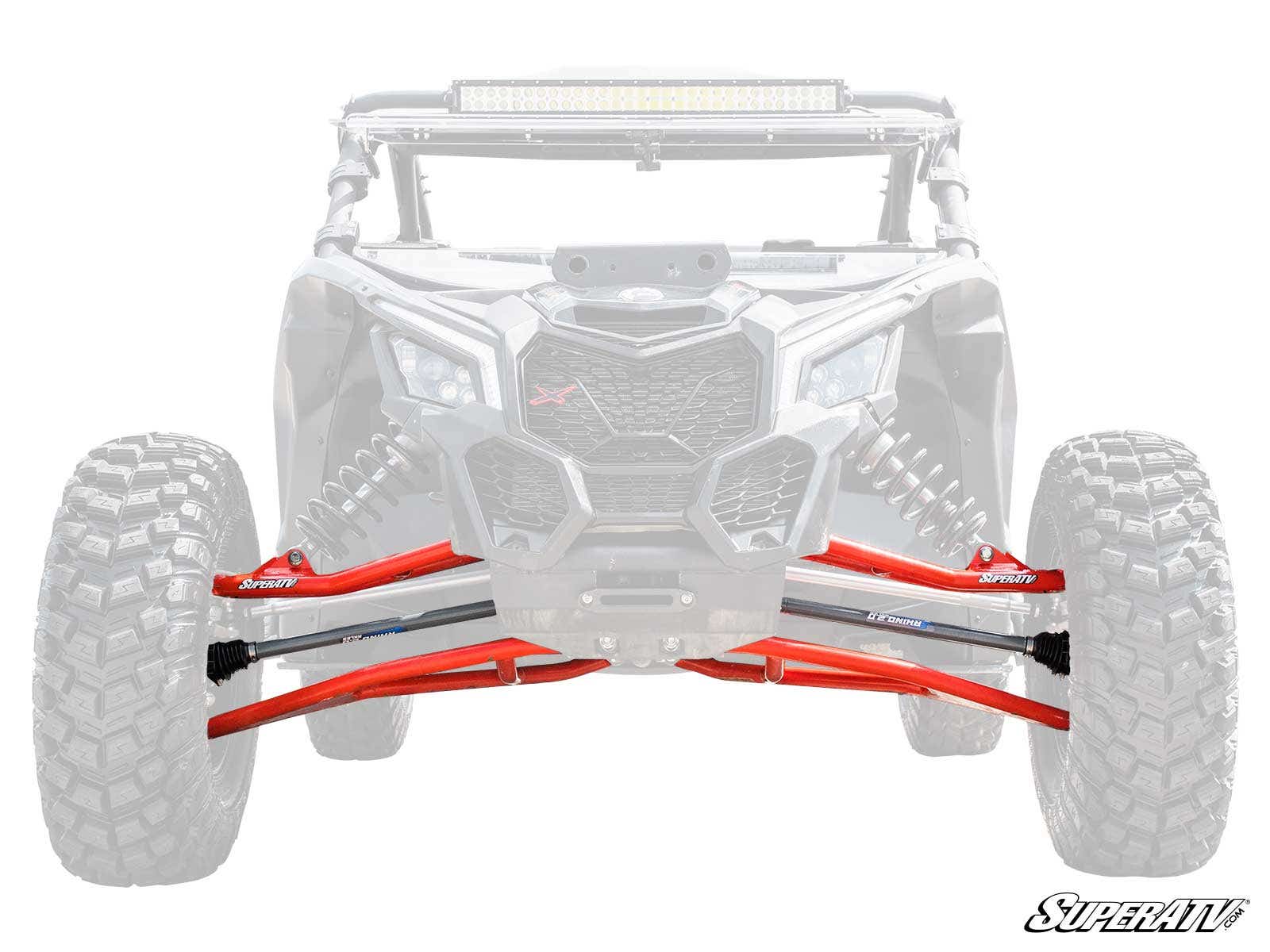 Front view of an off-road vehicle with faded chassis and wheels, highlighting bright red A-arms and suspension from the Can-Am Maverick X3 Long Travel Kit. The SuperATV logo appears in the bottom right, with A-arms centered prominently.