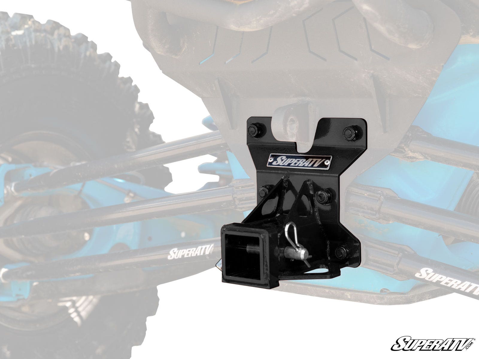 A black metal Can-Am Maverick X3 Rear Receiver Hitch is mounted on a blue off-road vehicle frame. The background features an enlarged, faded view of the suspension and wheels, with the SuperATV logo shown on the hitch and in the bottom right corner.