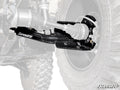Close-up view of black Can-Am Outlander High-Clearance 2 Rear Offset Trailing Arms labeled SuperATV, attached to a UTV’s rear wheel assembly, with the wheel and suspension parts partially visible in the background, highlighting the trailing arms.