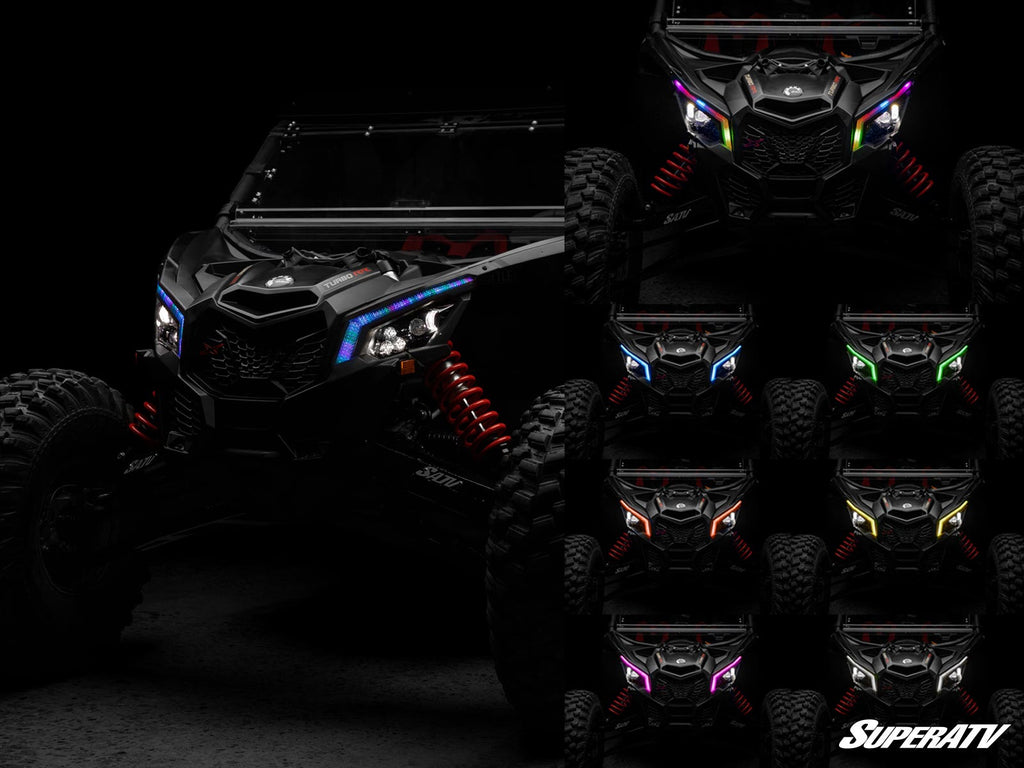 A Can-Am Maverick X3 with black body and red suspension is shown in low light, featuring Fang Lights headlights in eight colors: white, blue, cyan, green, purple, orange, red, and yellow. SuperATV appears in white text at the bottom right.