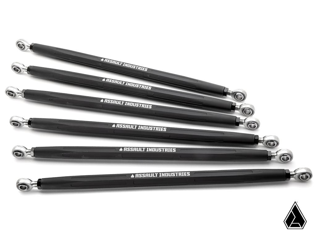 Six black Turret Style Heavy Duty Radius Rods for Can-Am Maverick X3, each with silver joints and ASSAULT INDUSTRIES in white text, are arranged diagonally on a white background. The Assault Industries logo is at the lower right.